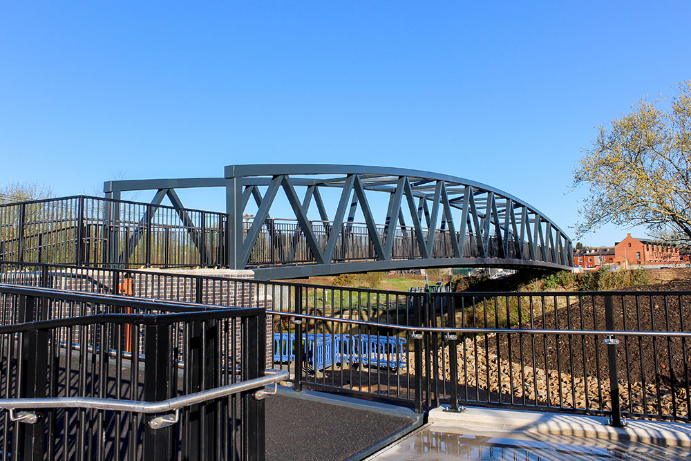A large green metal bridge over a river. 