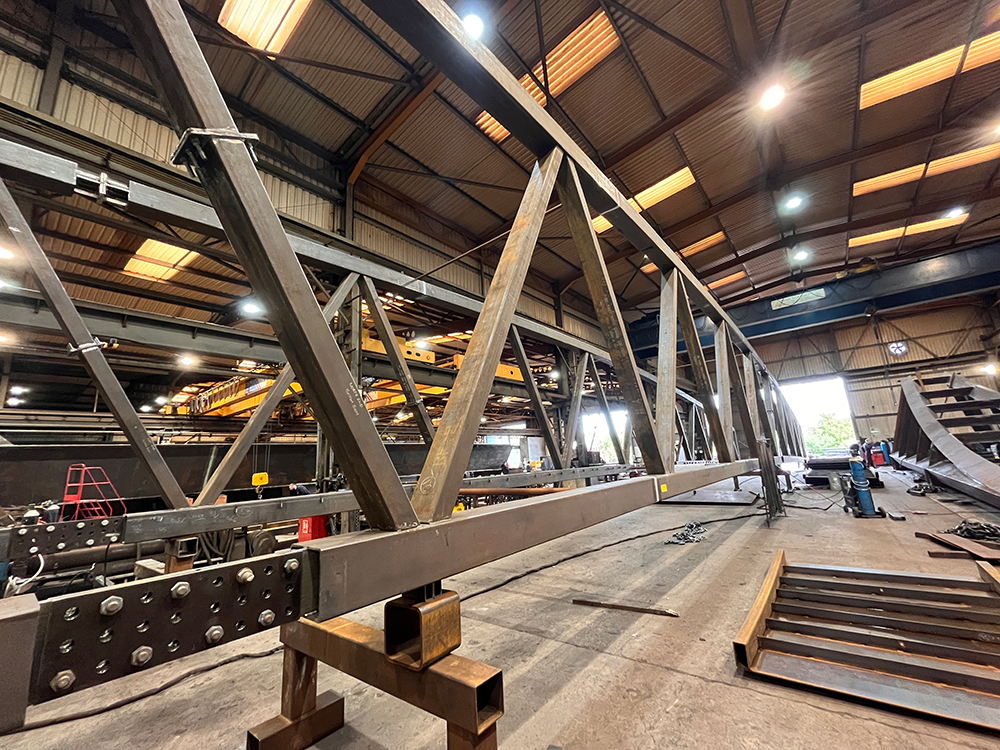 A large metal bridge under construction in a large warehouse
