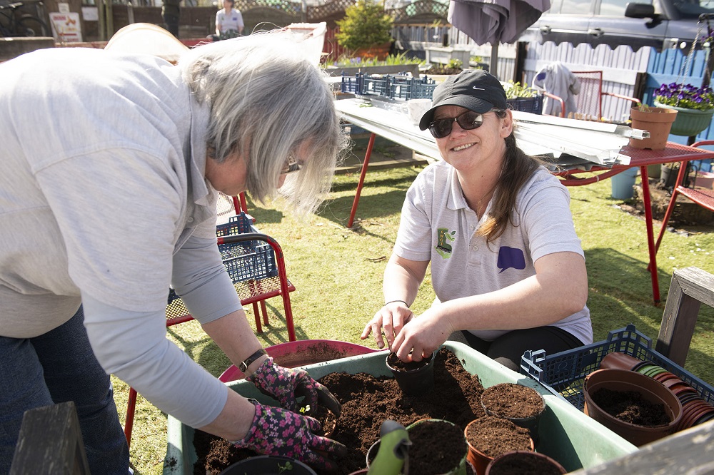 Two women preparing plant pots.