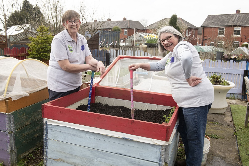 Two women preparing a large planter.