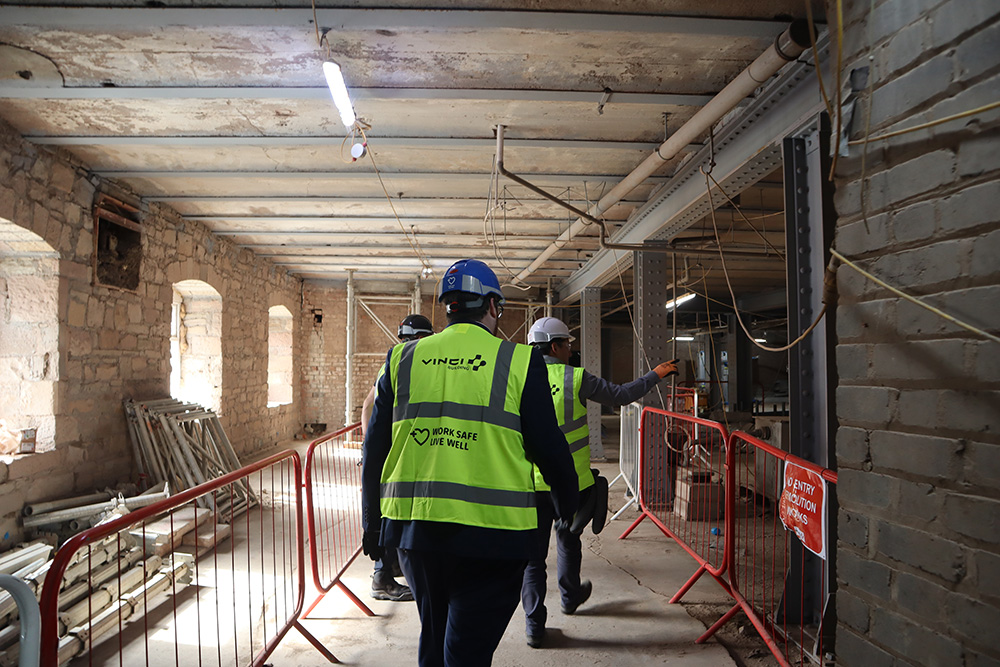 People wearing safety clothing, in a building basement, inspecting renovation works