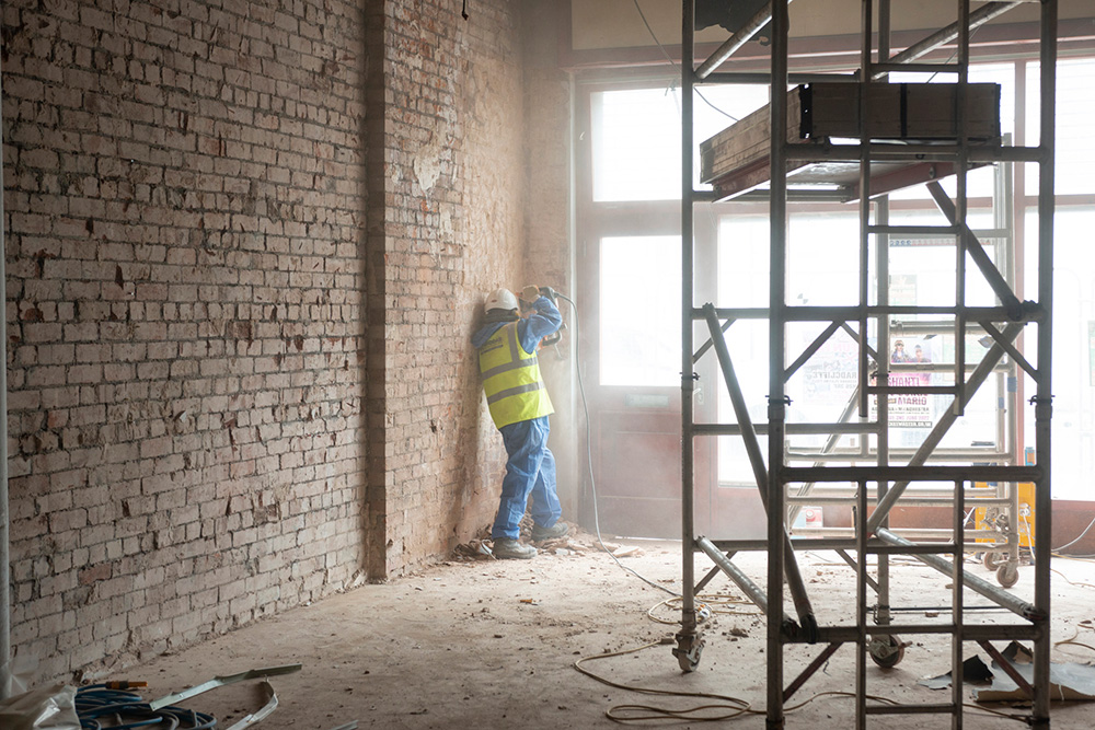 A person wearing safety clothing doing construction work inside a building