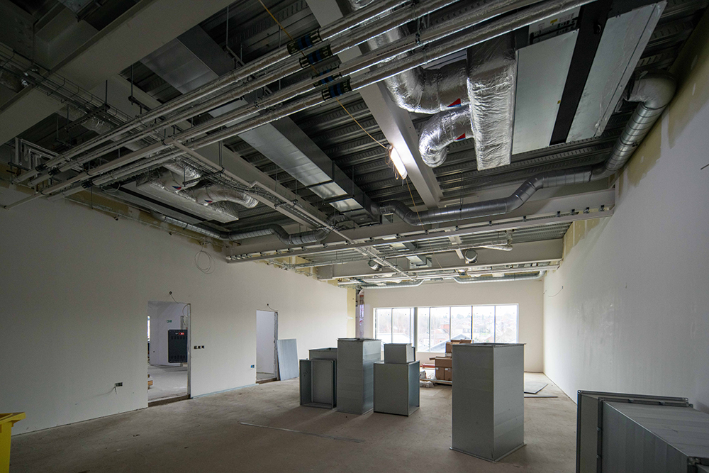 Pipework visible in the ceiling of a large room there are large boxes covering the floor area