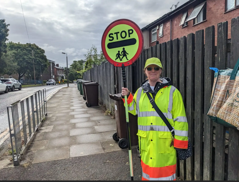 An on duty fully uniformed crossing guard holding her lollipop stick.