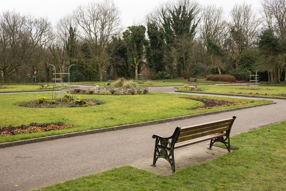 A bench on a pathway and gardens.