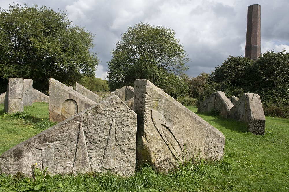 Large stones on a field with chimney in background.