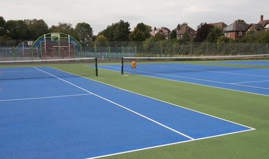 Blue surfaced tennis courts and nets.