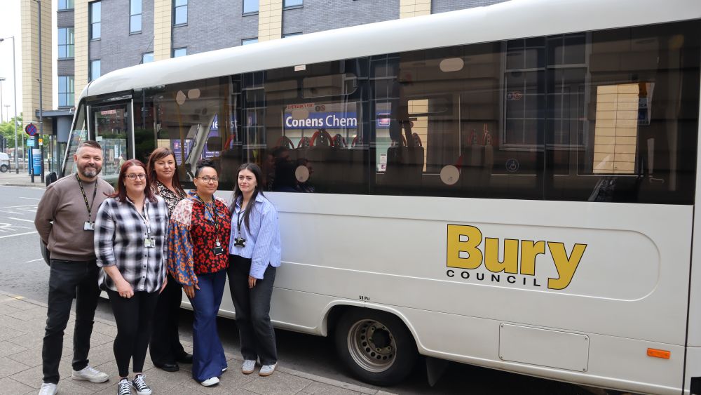A group of people standing next to a Bury Council branded white van.