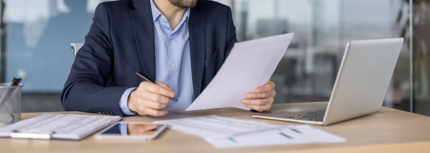 A professional working on documents and a laptop