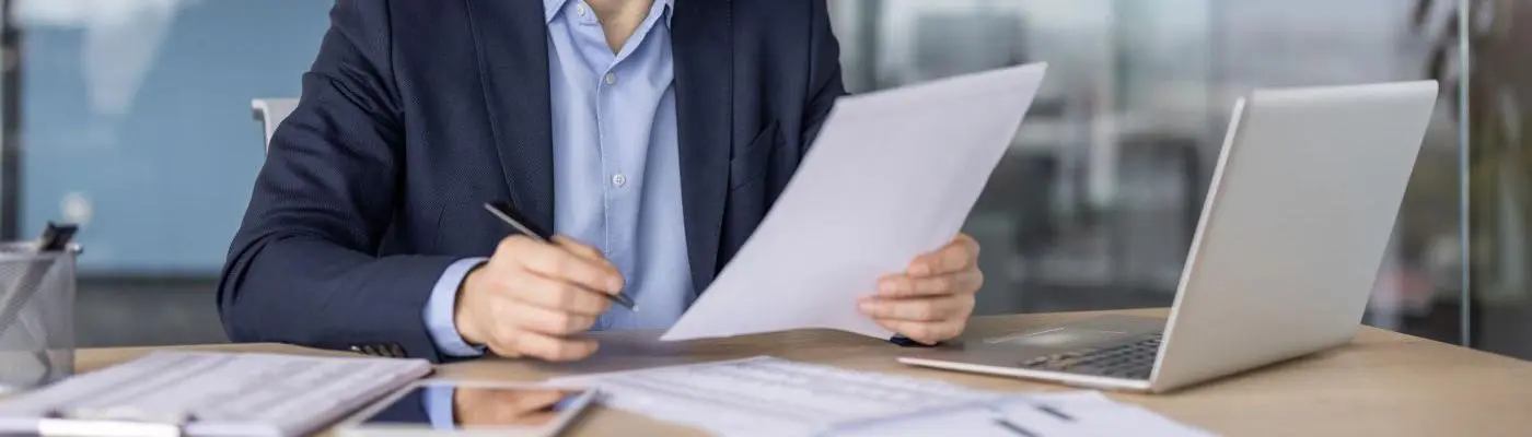 A professional working on documents and a laptop