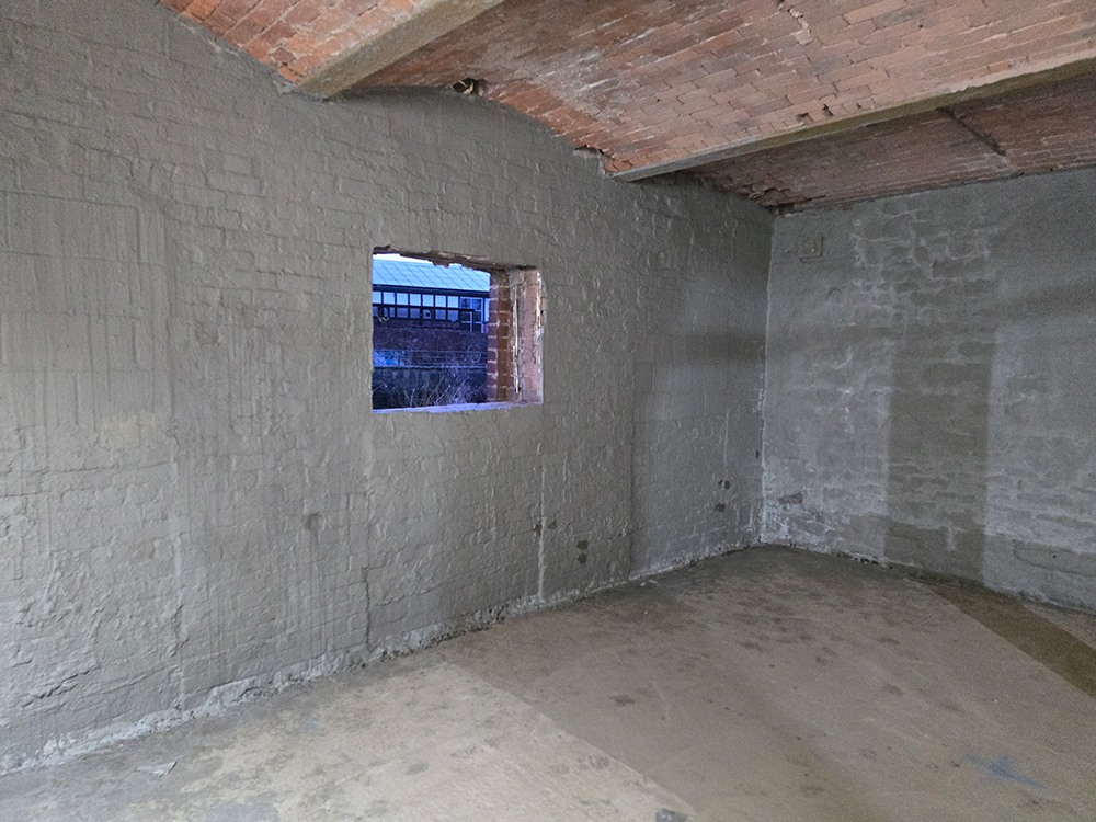 An empty room with brick walls and concrete floor and ceiling