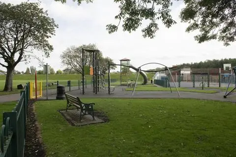 Swings, bench and climbing frame in play area.