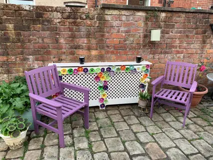 Two purple chairs and plant pots on a cobbled street