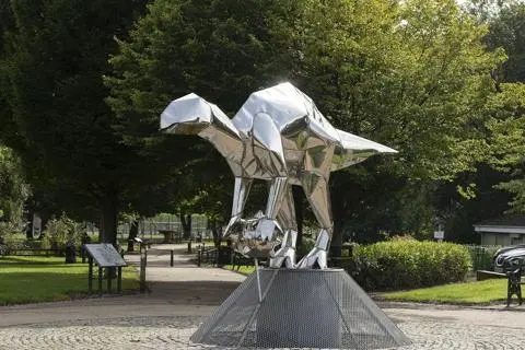 Metal dinosaur sculpture on plinth.