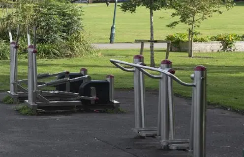 Gym equipment by grass and trees.