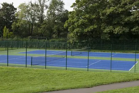 Fenced blue surfaced tennis courts.